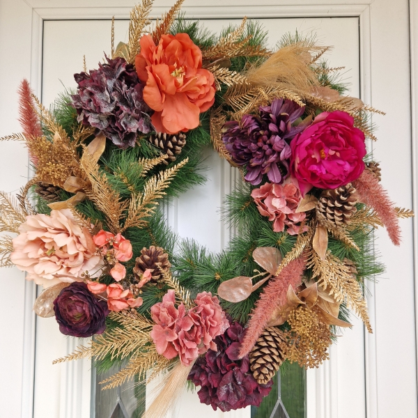 Faux flower Christmas wreath with peonies, hydrangeas, ranunculus, skimmia, pine cones, and gold accents on a 50cm faux pine ring