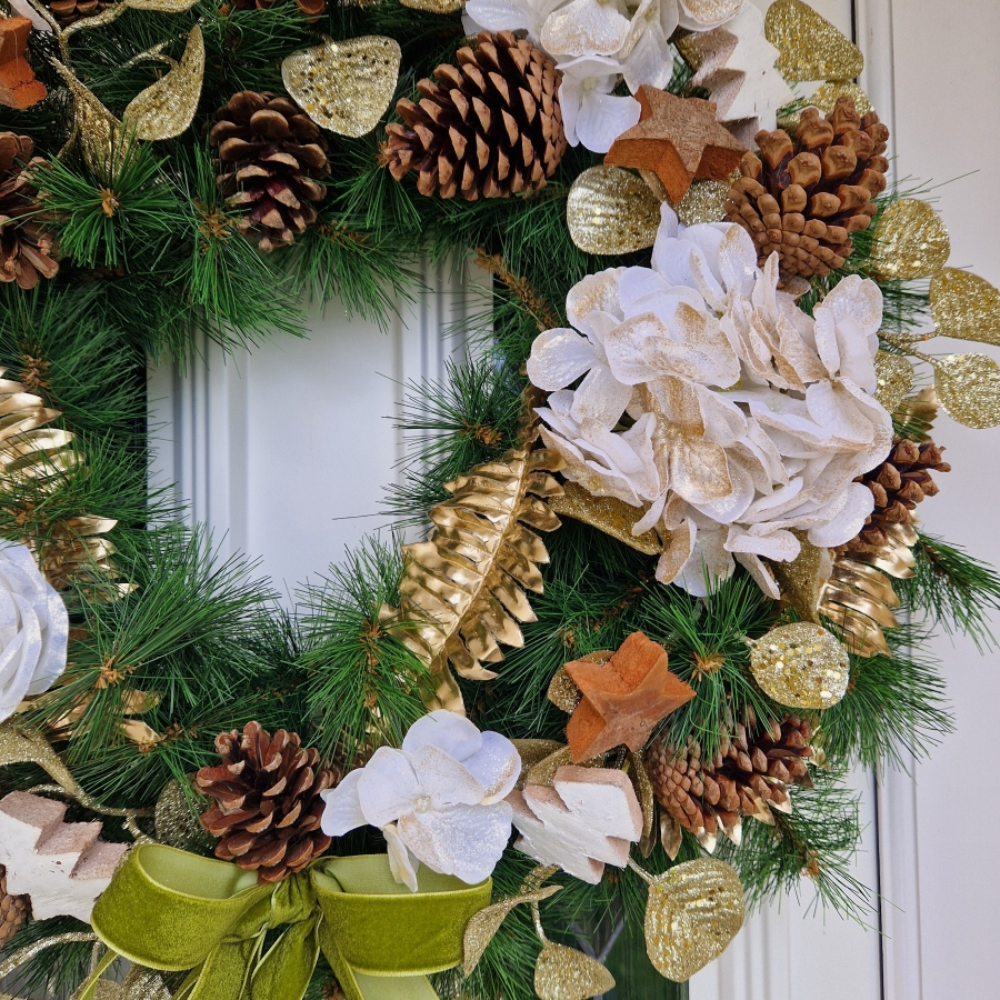 White faux flower Christmas wreath with roses, hydrangeas, gold accents, coco stars, pine cones, and velvet bow on a 50cm faux pine ring