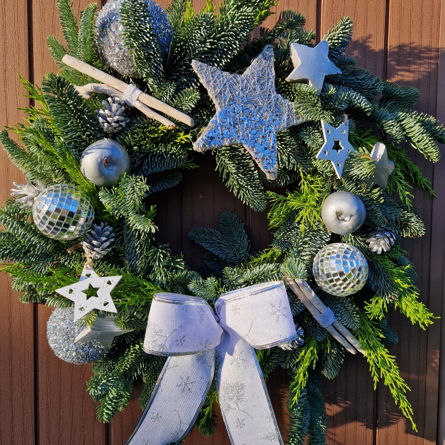 Christmas door wreath with fresh pine, conifers, silver sisal star, wooden and coco stars, waxed apples, pine cones, and mirror baubles.