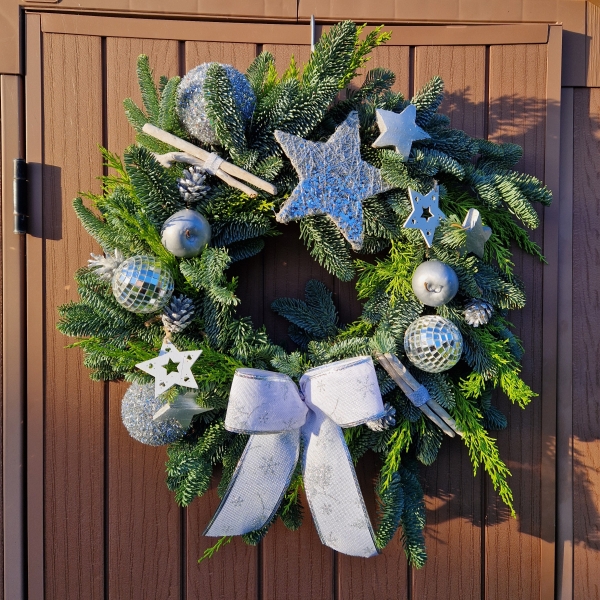 Christmas door wreath with fresh pine, conifers, silver sisal star, wooden and coco stars, waxed apples, pine cones, and mirror baubles.
