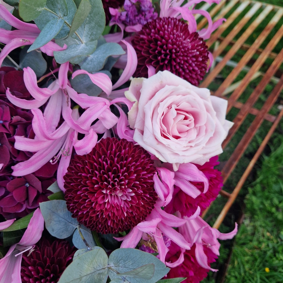 Chyngton autumn bouquet in rich pink and plum tones, featuring nerines, chrysanthemum blooms, roses, carnations, and statice in a lush, seasonal arrangement