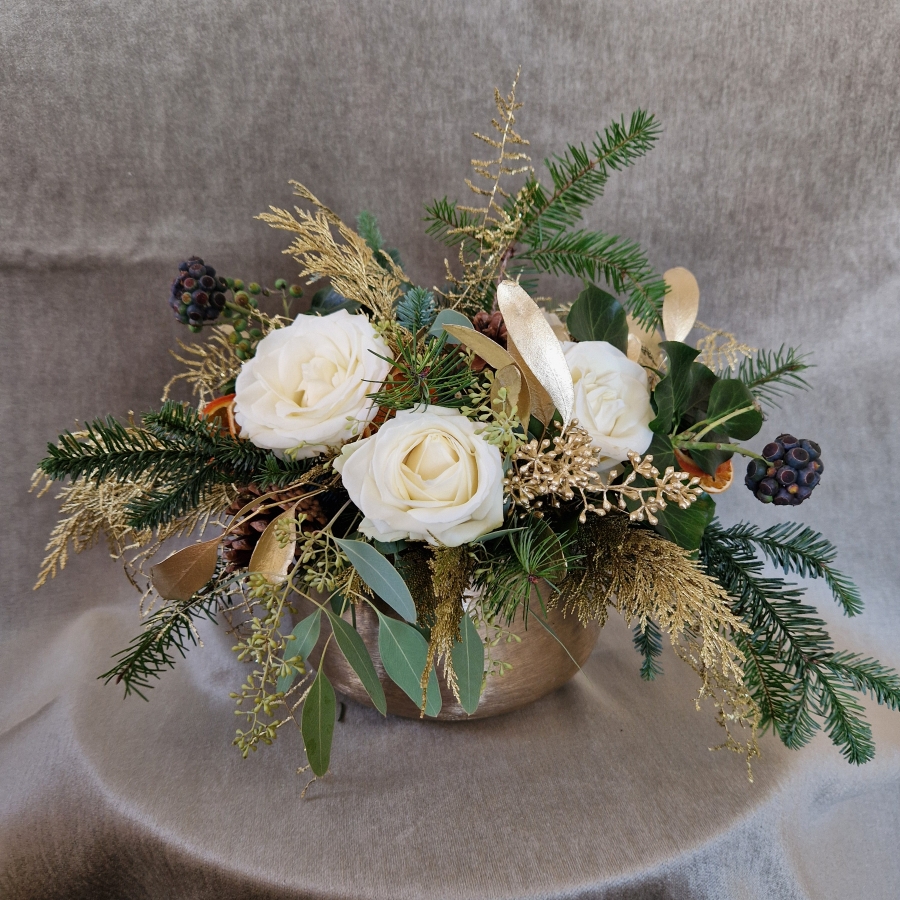 The Gilded Rose arrangement with white roses, gold eucalyptus, fresh pine, conifer, and ivy berry in a brushed gold bowl