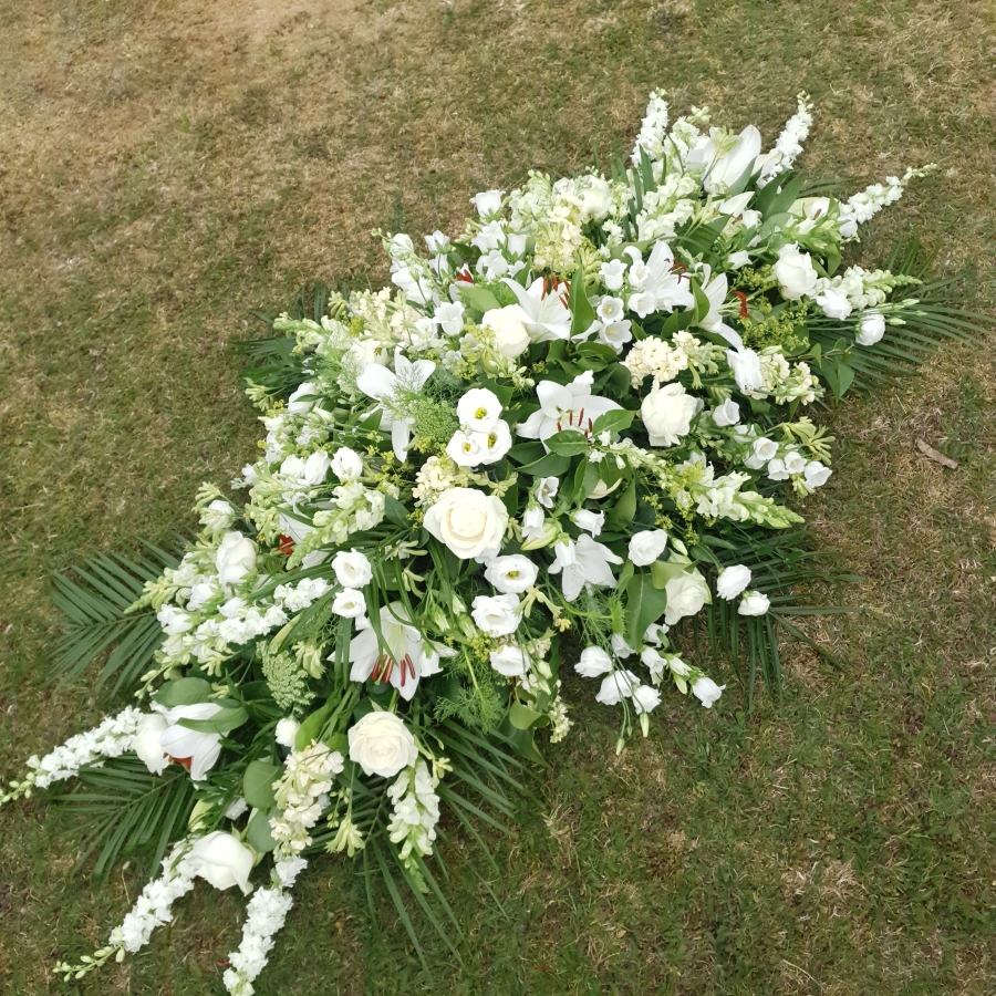 Funeral coffin spray in classic seasonal white and green flowers