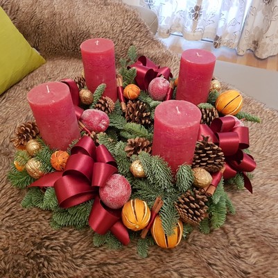 Luxury Christmas advent wreath with four burgundy pillar candles, velvet bows, fresh Nobilis pine, pine cones, cinnamon sticks, dried orange and apple slices, chillies, and waxed apples
