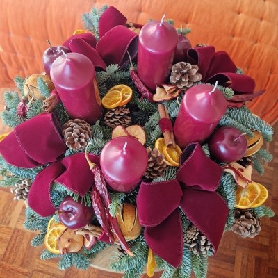 Luxury Christmas advent wreath with four burgundy pillar candles, velvet bows, fresh Nobilis pine, pine cones, cinnamon sticks, dried orange and apple slices, chillies, and waxed apples