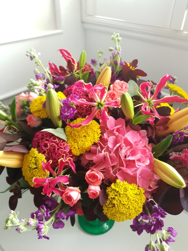 Brighton Bloom summer bouquet featuring vivid gloriosa, hot pink roses and celosia, golden achillea, purple scented matthiola, and large hydrangea—arranged with dramatic colour contrasts - inspired by a vibrant seafront.