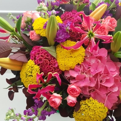 Brighton Bloom summer bouquet featuring vivid gloriosa, hot pink roses and celosia, golden achillea, purple scented matthiola, and large hydrangea—arranged with dramatic colour contrasts - inspired by a vibrant seafront.