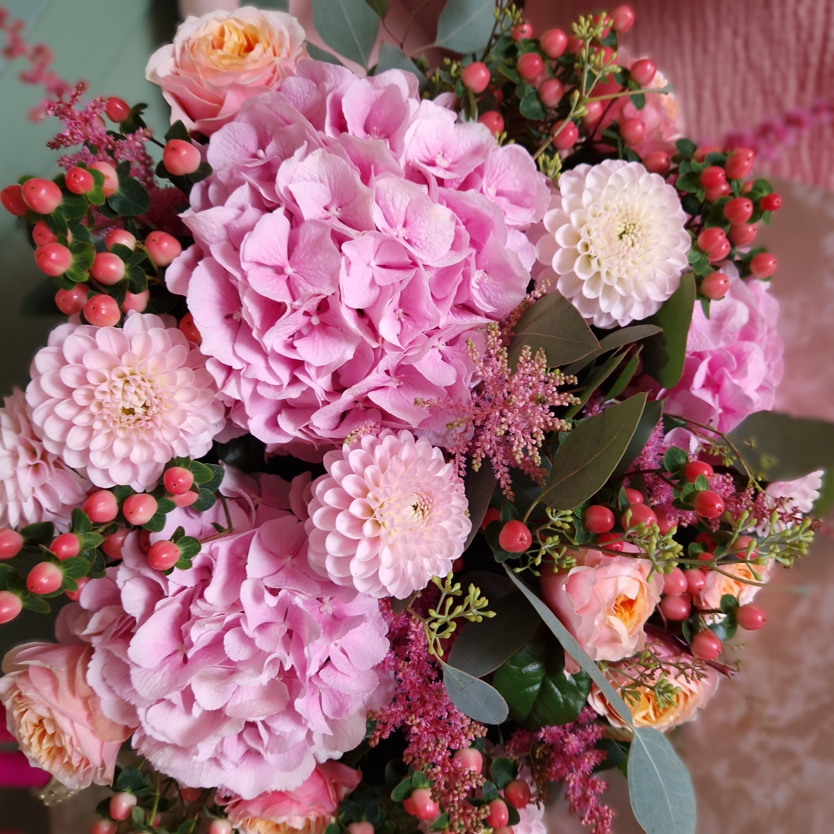 Borde Hill bouquet with pink hydrangeas, apricot garden roses, berries and astilbe displayed in a clear glass vase