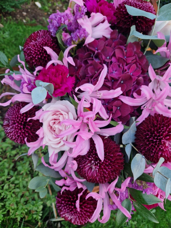 Chyngton autumn bouquet in rich pink and plum tones, featuring nerines, chrysanthemum blooms, roses, carnations, and statice in a lush, seasonal arrangement