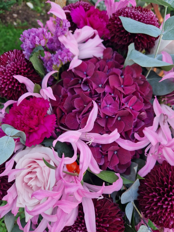 Chyngton autumn bouquet in rich pink and plum tones, featuring nerines, chrysanthemum blooms, roses, carnations, and statice in a lush, seasonal arrangement