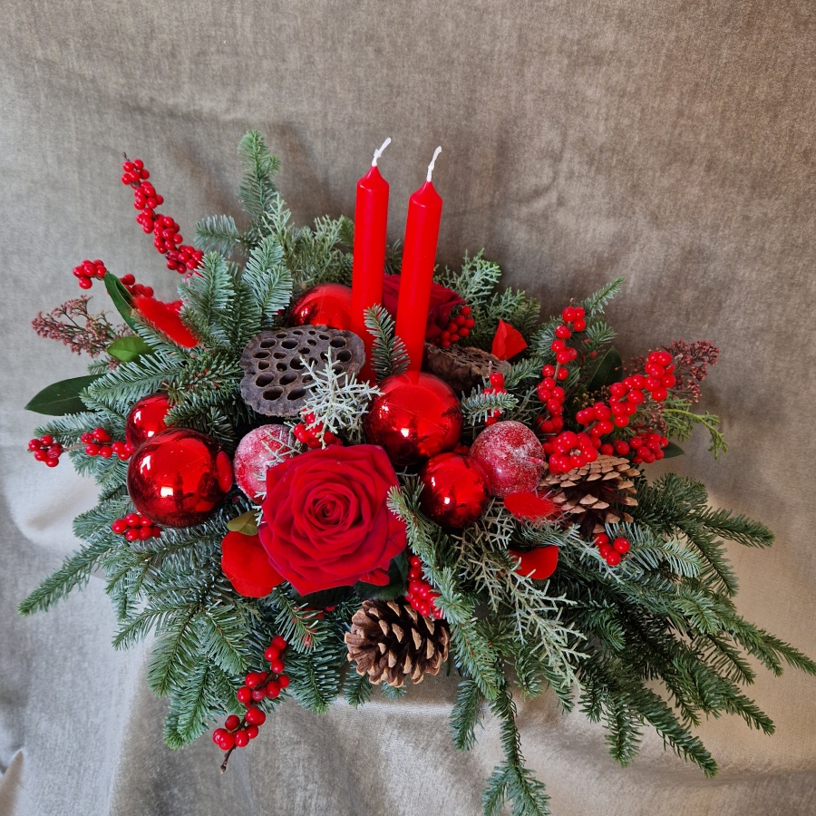 Crimson Eve Christmas centrepiece with red candles, deep red roses, fresh pine, waxed apples, pine cones, red baubles, and ilex berries