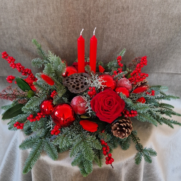 Crimson Eve Christmas centrepiece with red candles, deep red roses, fresh pine, waxed apples, pine cones, red baubles, and ilex berries