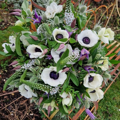 Spring bouquet with white Mistral Anemones, purple Clematis, Lysimachia, and white sea holly, inspired by East Dean’s cottage gardens and coastal charm.