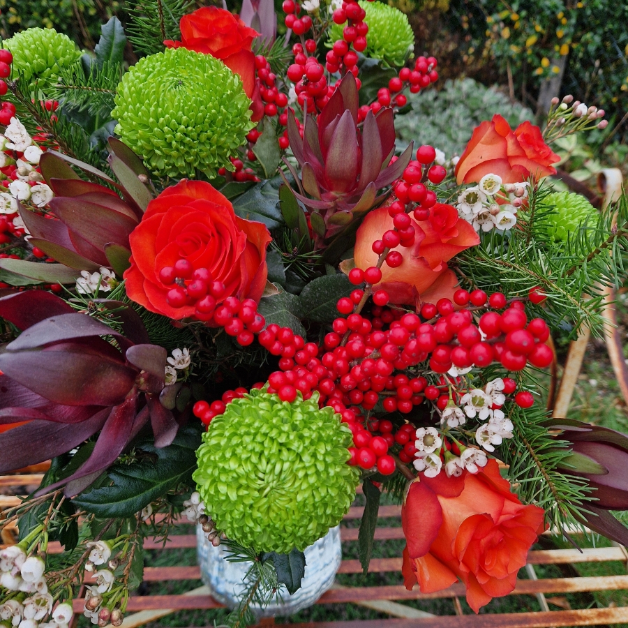 Christmas bouquet with burnt orange roses, ilex berries, green chrysanthemums, pine foliage, and seasonal fillers