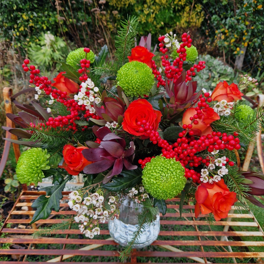 Christmas bouquet with burnt orange roses, ilex berries, green chrysanthemums, pine foliage, and seasonal fillers