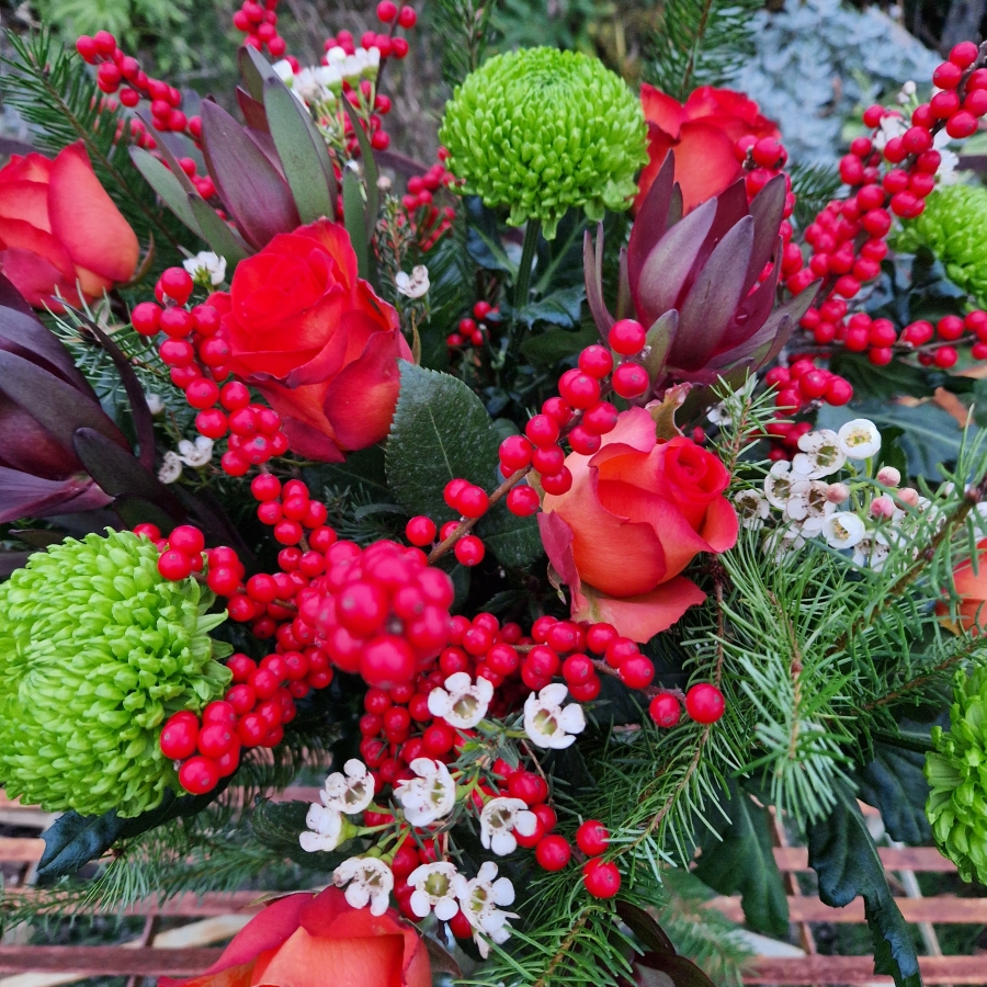 Christmas bouquet with burnt orange roses, ilex berries, green chrysanthemums, pine foliage, and seasonal fillers
