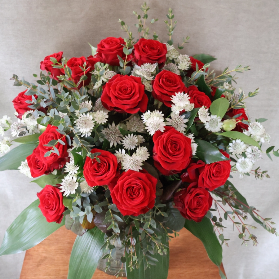 A hand‑tied luxury Valentine’s bouquet of premium red roses, delicate white Astrantia and natural foliage, gift‑wrapped and presented in a kraft water‑holding bouquet box.