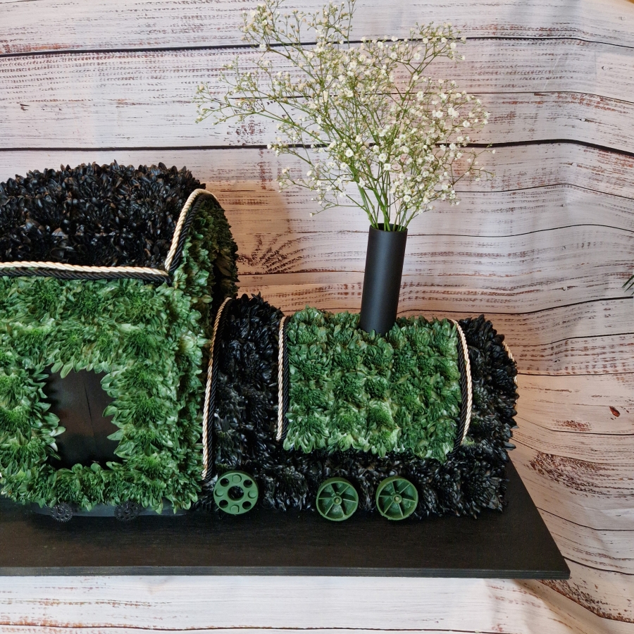 3D funeral tribute shaped like a steam train with coal carriage, crafted in green and black flowers