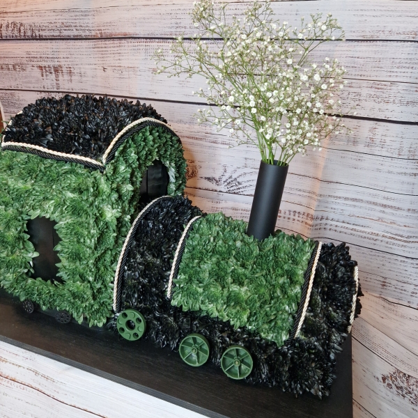 3D funeral tribute shaped like a steam train with coal carriage, crafted in green and black flowers