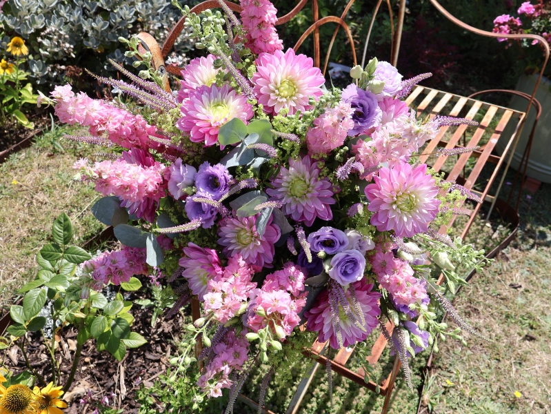 Summer garden bouquet in soft pinks and lilacs, featuring dahlia, delphinium larkspur, veronica, lisianthus, and alchemilla, styled in a wild, seasonal arrangement.