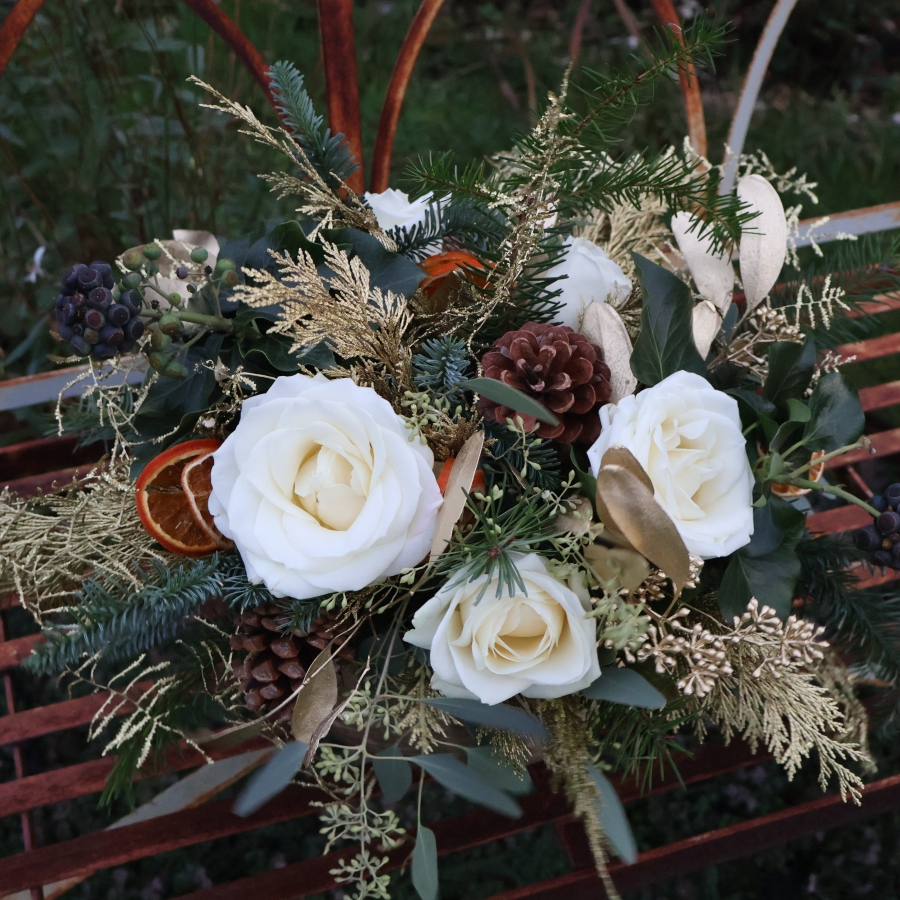 The Gilded Rose arrangement with white roses, gold eucalyptus, fresh pine, conifer, and ivy berry in a brushed gold bowl