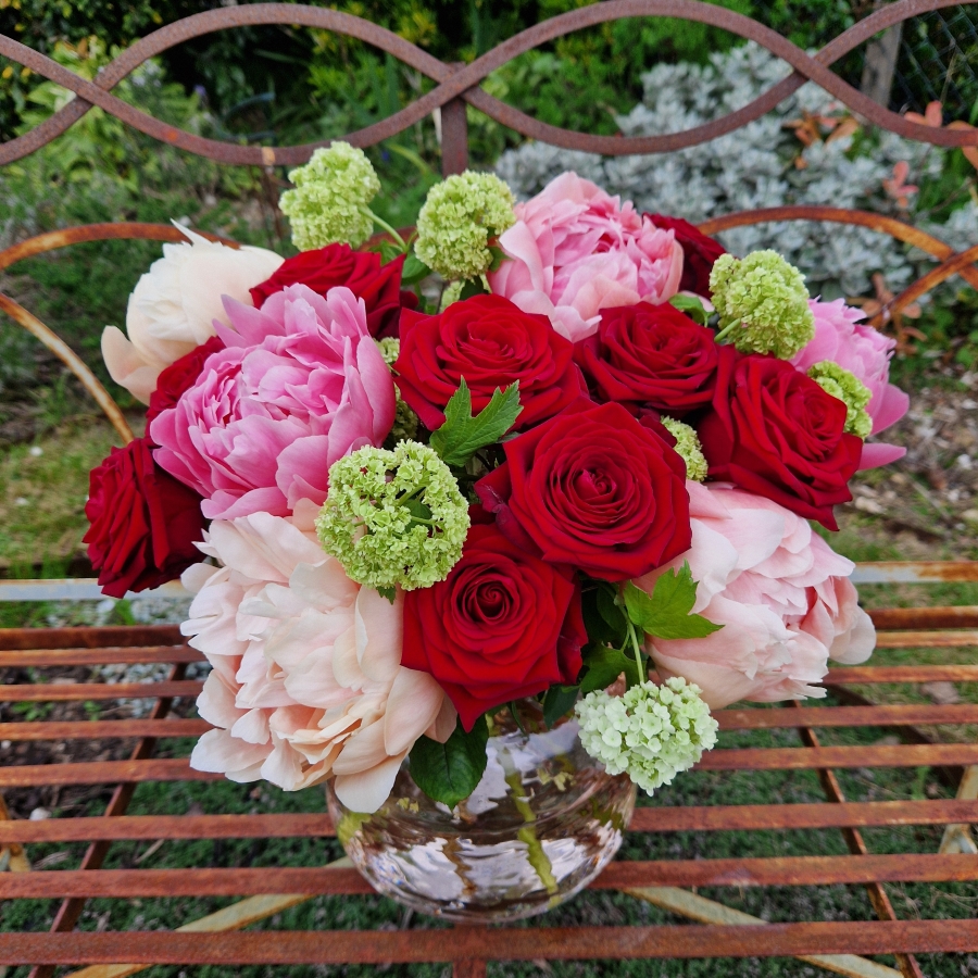 Spring vase of coral peonies and velvet red roses