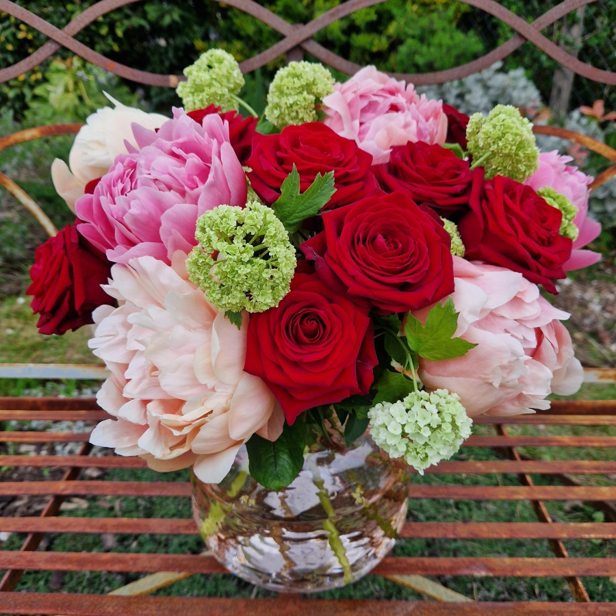 Spring vase of coral peonies and velvet red roses