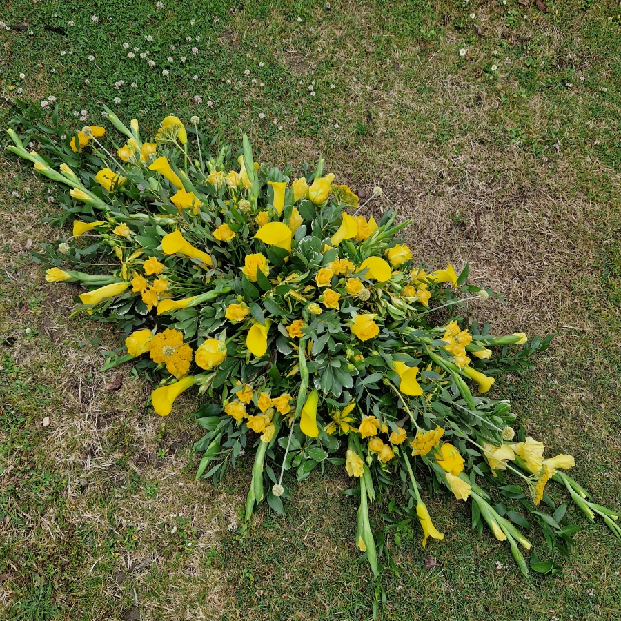 Funeral coffin spray with yellow calla lilies and roses