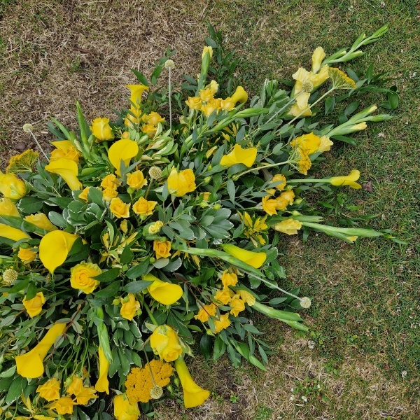 Funeral coffin spray with yellow calla lilies and roses