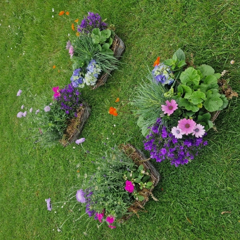 Planted garden tribute combining a biodegradable heart, wreath, and planted baskets arranged to dress the coffin and hearse.