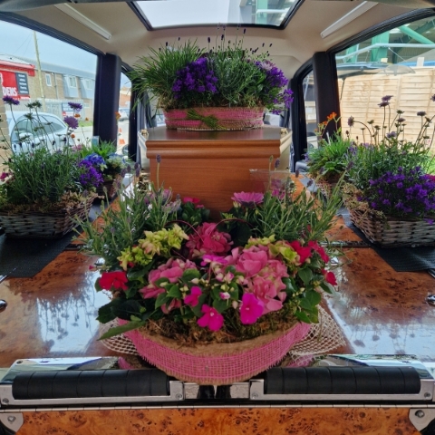 Planted garden tribute combining a biodegradable heart, wreath, and planted baskets arranged to dress the coffin and hearse.