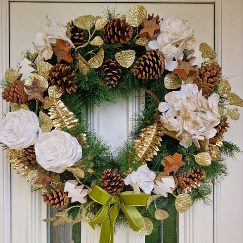 White faux flower Christmas wreath with roses, hydrangeas, gold accents, coco stars, pine cones, and velvet bow on a 50cm faux pine ring