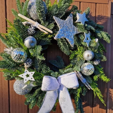 Christmas door wreath with fresh pine, conifers, silver sisal star, wooden and coco stars, waxed apples, pine cones, and mirror baubles.