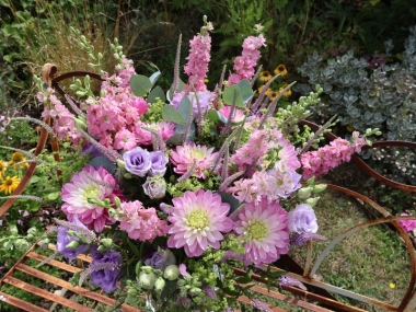 Summer garden bouquet in soft pinks and lilacs, featuring dahlia, delphinium larkspur, veronica, lisianthus, and alchemilla, styled in a wild, seasonal arrangement.