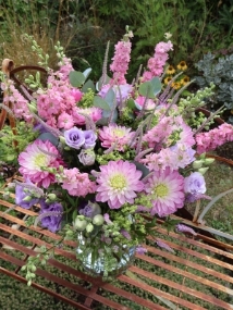 Summer garden bouquet in soft pinks and lilacs, featuring dahlia, delphinium larkspur, veronica, lisianthus, and alchemilla, styled in a wild, seasonal arrangement.