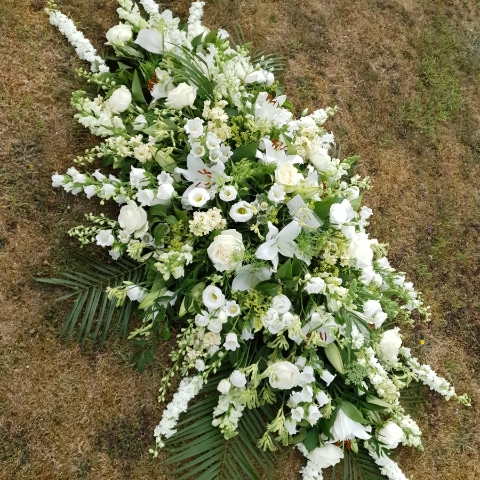 Funeral coffin spray in classic seasonal white and green flowers