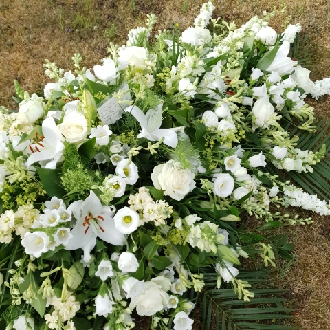 Funeral coffin spray in classic seasonal white and green flowers