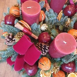 Luxury Christmas advent wreath with four burgundy pillar candles, velvet bows, fresh Nobilis pine, pine cones, cinnamon sticks, dried orange and apple slices, chillies, and waxed apples