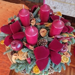 Luxury Christmas advent wreath with four burgundy pillar candles, velvet bows, fresh Nobilis pine, pine cones, cinnamon sticks, dried orange and apple slices, chillies, and waxed apples