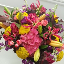 Brighton Bloom summer bouquet featuring vivid gloriosa, hot pink roses and celosia, golden achillea, purple scented matthiola, and large hydrangea—arranged with dramatic colour contrasts - inspired by a vibrant seafront.