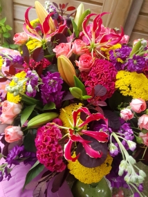 Brighton Bloom summer bouquet featuring vivid gloriosa, hot pink roses and celosia, golden achillea, purple scented matthiola, and large hydrangea—arranged with dramatic colour contrasts - inspired by a vibrant seafront.