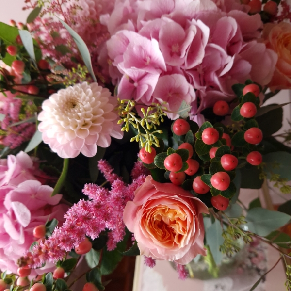 Borde Hill bouquet with pink hydrangeas, apricot garden roses, berries and astilbe displayed in a clear glass vase