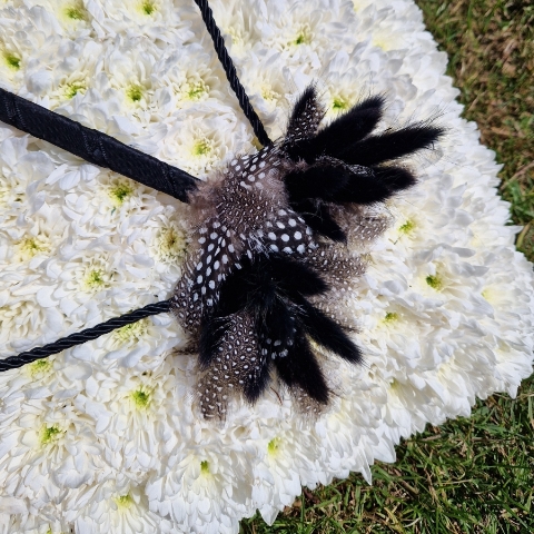 Bespoke funeral wreath with bow and arrow design made from black tie leaves on white chrysanthemum base