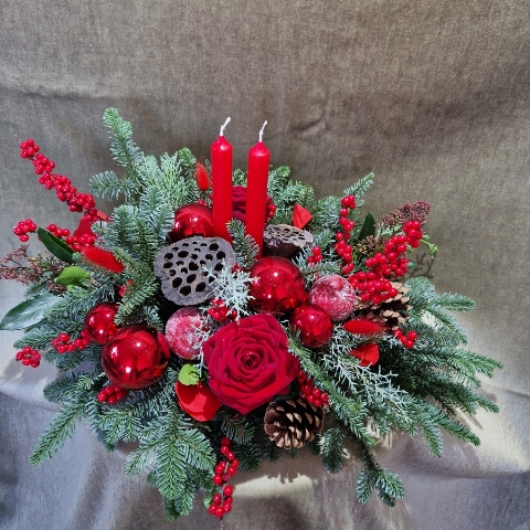Crimson Eve Christmas centrepiece with red candles, deep red roses, fresh pine, waxed apples, pine cones, red baubles, and ilex berries