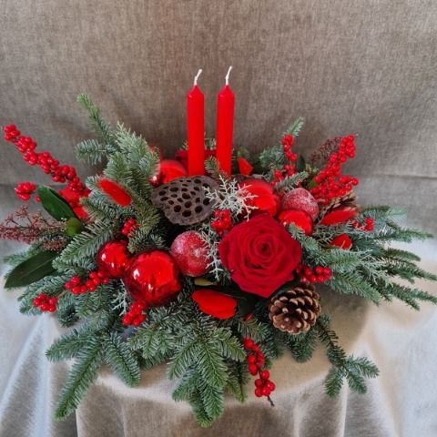 Crimson Eve Christmas centrepiece with red candles, deep red roses, fresh pine, waxed apples, pine cones, red baubles, and ilex berries