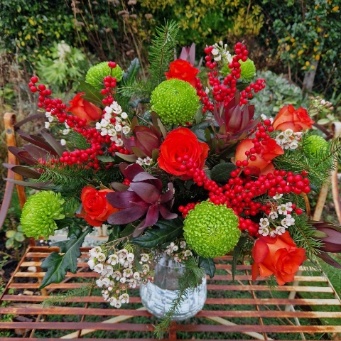 Christmas bouquet with burnt orange roses, ilex berries, green chrysanthemums, pine foliage, and seasonal fillers