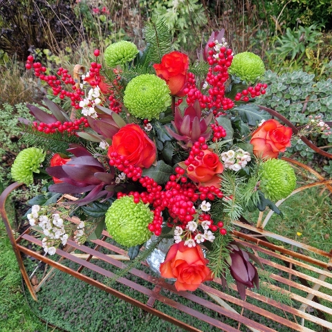 Christmas bouquet with burnt orange roses, ilex berries, green chrysanthemums, pine foliage, and seasonal fillers