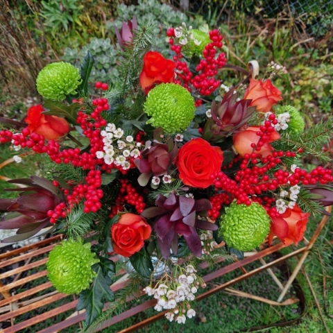 Christmas bouquet with burnt orange roses, ilex berries, green chrysanthemums, pine foliage, and seasonal fillers