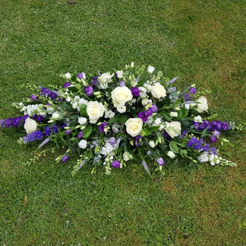 Seasonal coffin spray in purple white flowers