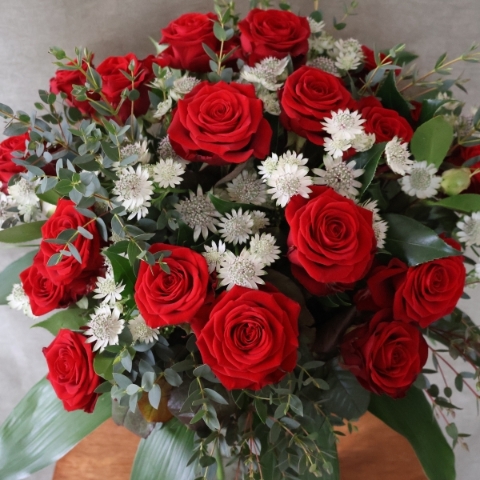 A hand‑tied luxury Valentine’s bouquet of premium red roses, delicate white Astrantia and natural foliage, gift‑wrapped and presented in a kraft water‑holding bouquet box.